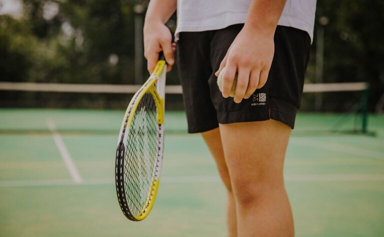 A man holding a tennis racket and ball on a tennis court