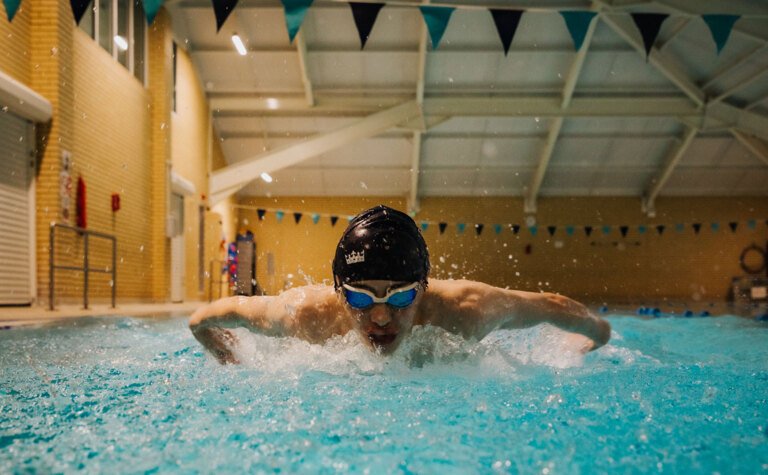 A teenage boy doing butterfly in an indoor swimming pool