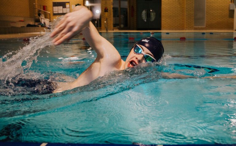 A teenage boy doing front crawl in an indoor swimming pool