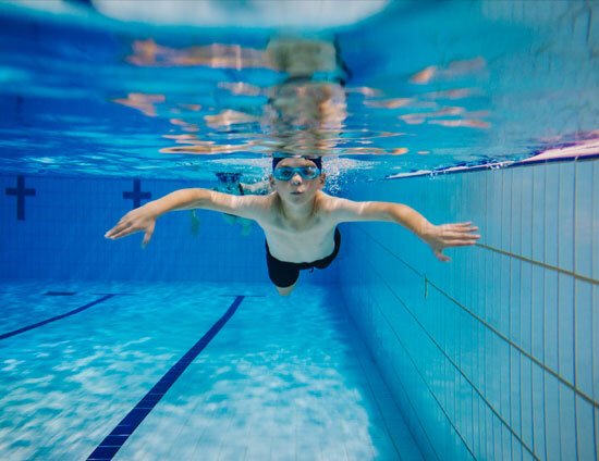 Young boy swimming underwater in an indoor swimming pool