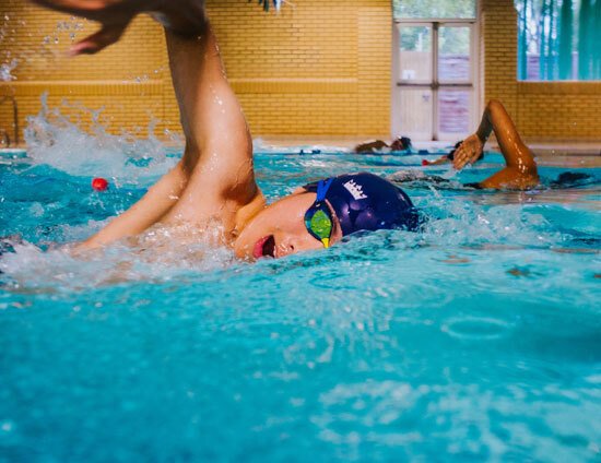 Teenage boy doing front crawl in indoor swimming pool